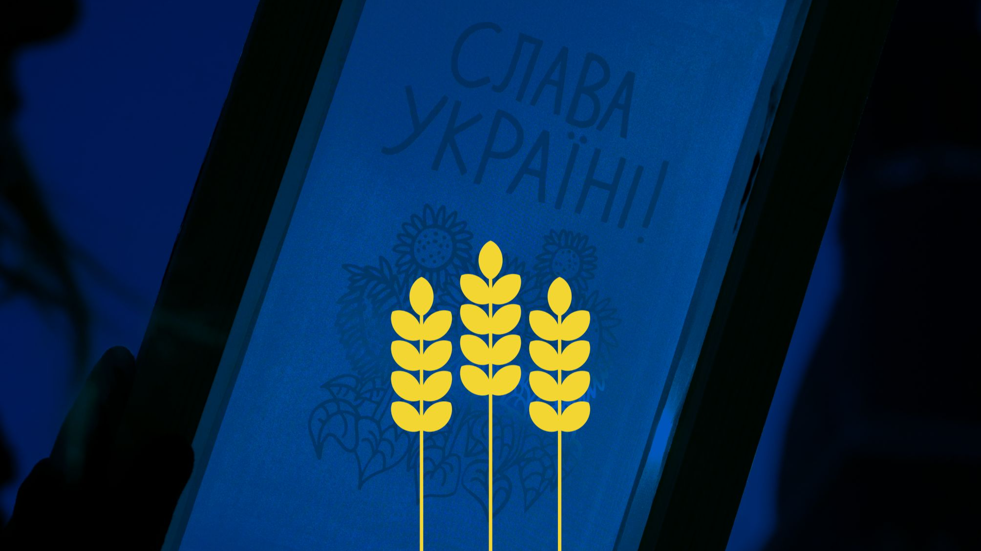 Pasākuma plakāts - uz zila fona sietspiede ar uzrakstu Slava Ukrainai un trīs dzeltenām vārpām